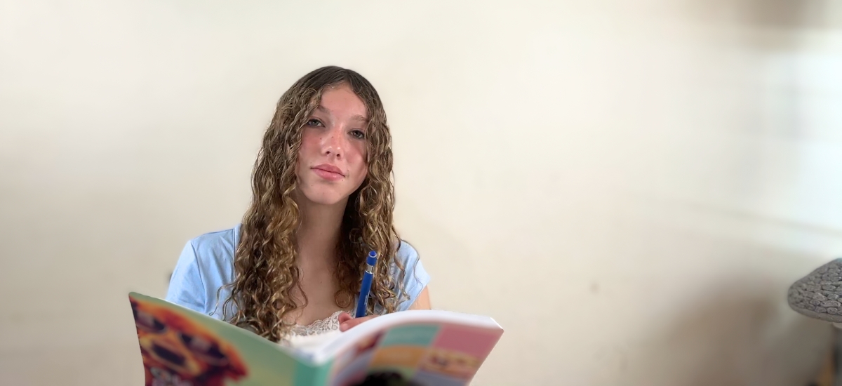 a White teen taking notes during a tutoring session