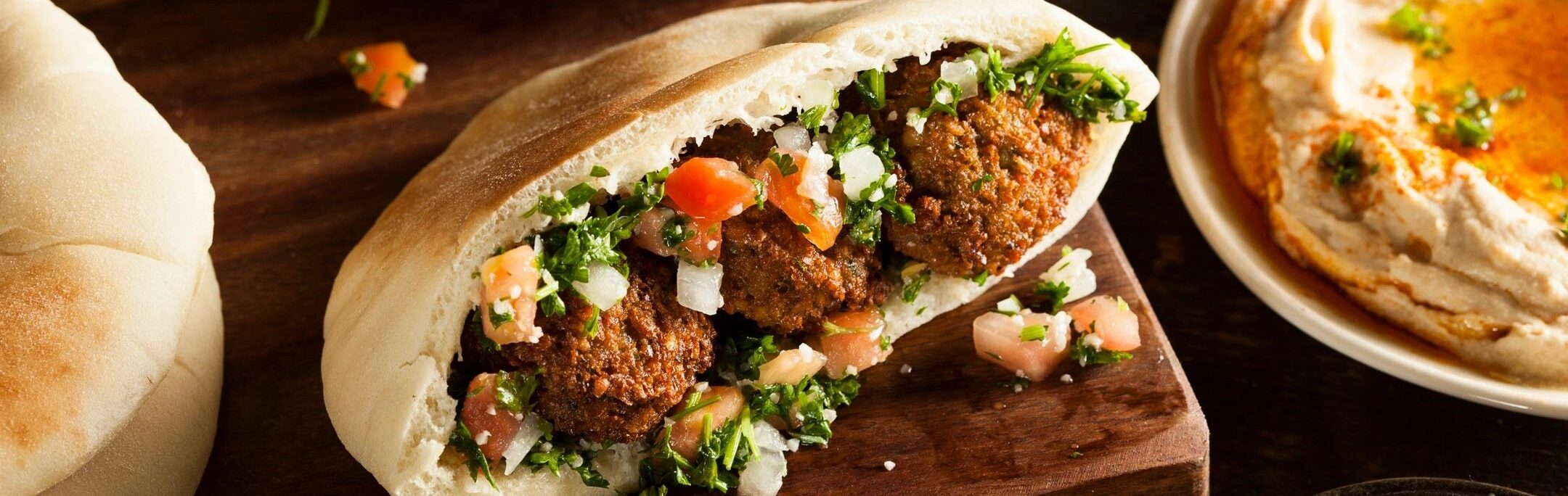 a pita bread with meatballs or falafel and vegetables on a cutting board